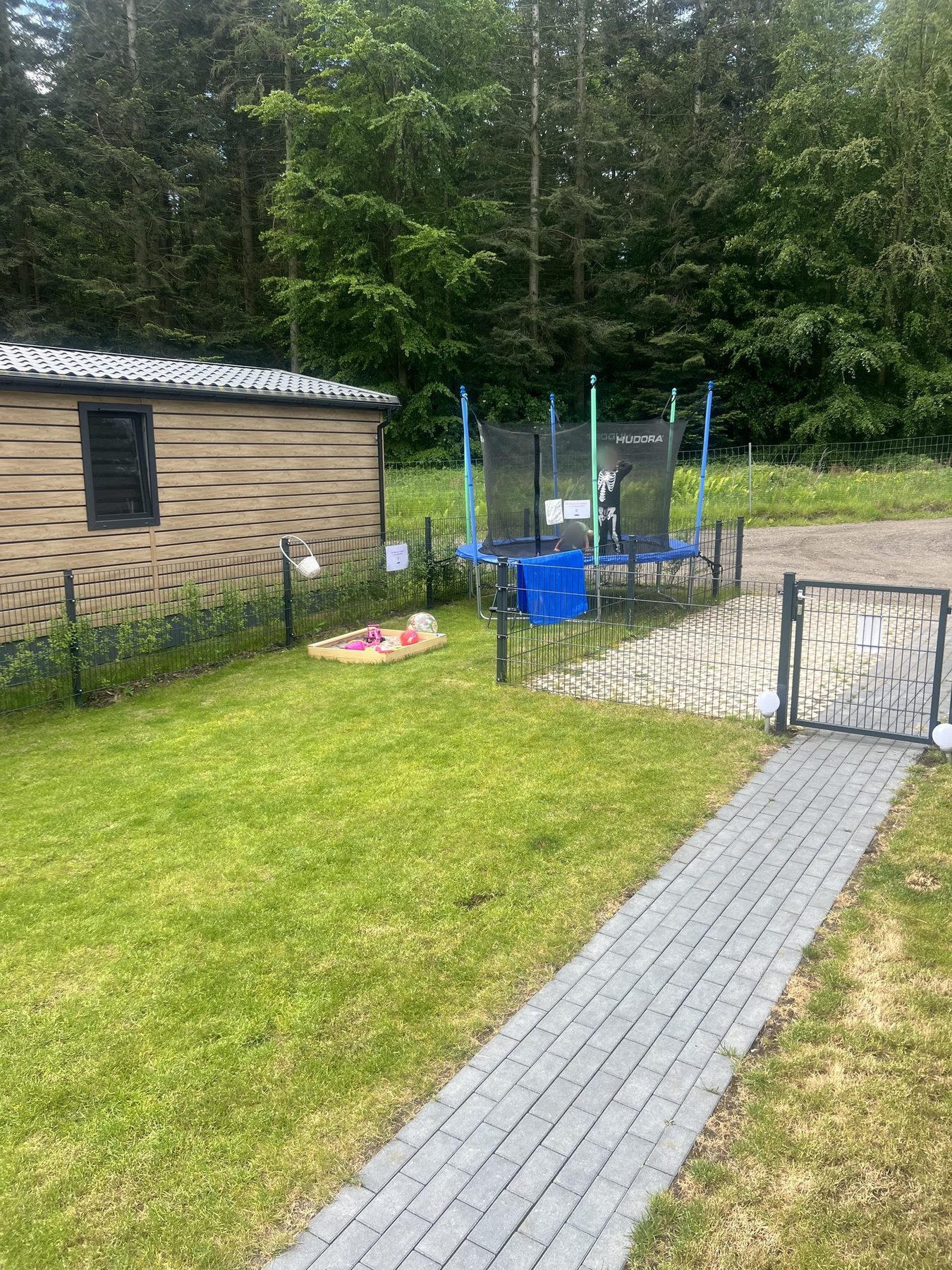 Trampolin und Sandspielzeug im eingezäunten Garten