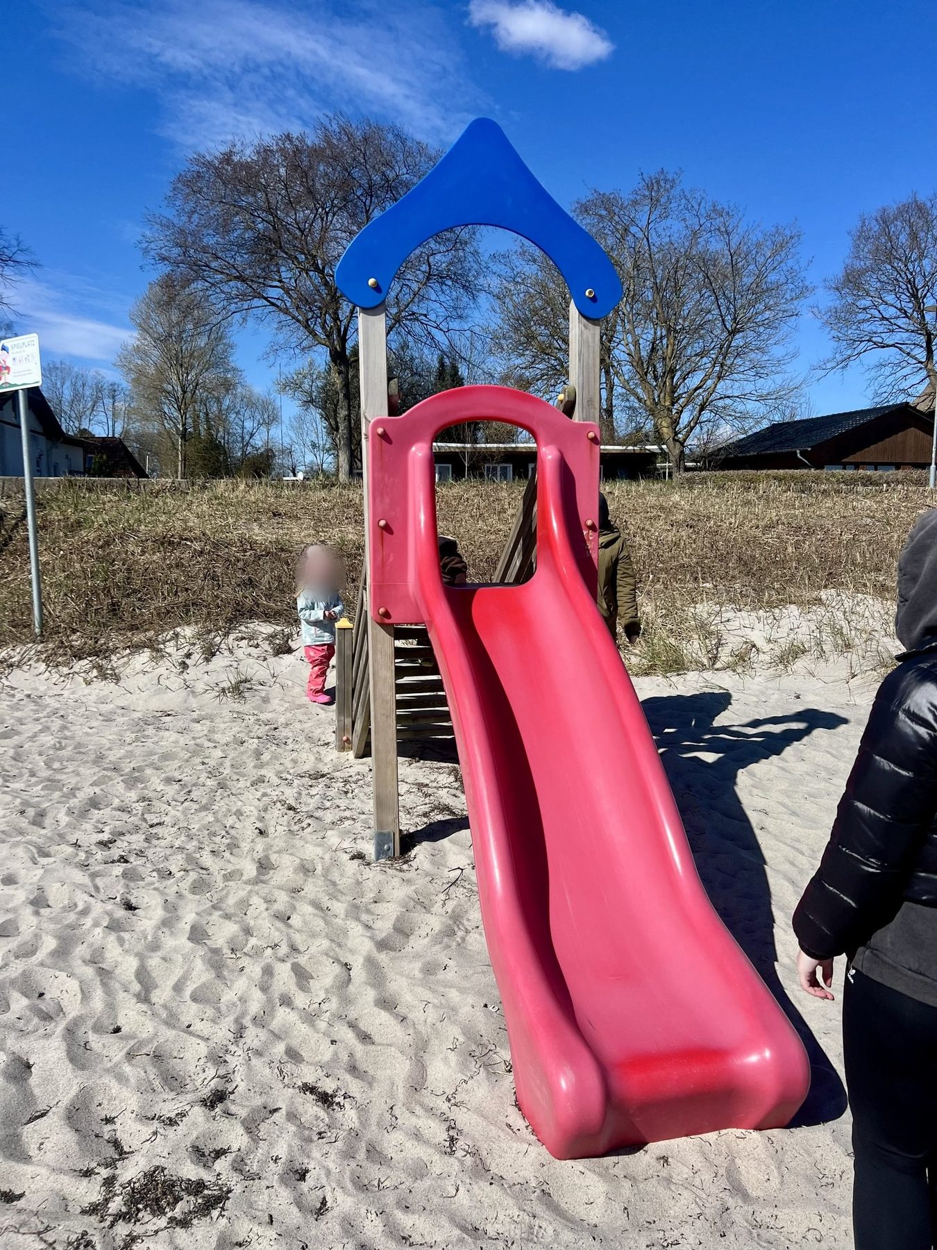 Kind warm angezogen am Spielplatz hinter dem Strand